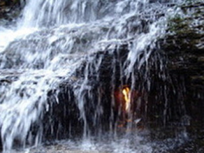 Fire burning naturally in midst of waterfall